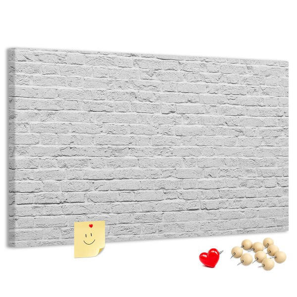 Tablero de anuncios con diseño de pared de ladrillo blanco y chinchetas de colores