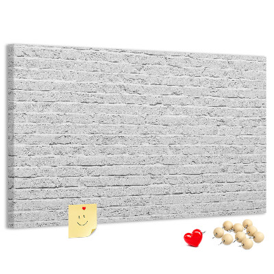 Tablero de anuncios con diseño de pared de ladrillo blanco y chinchetas de colores