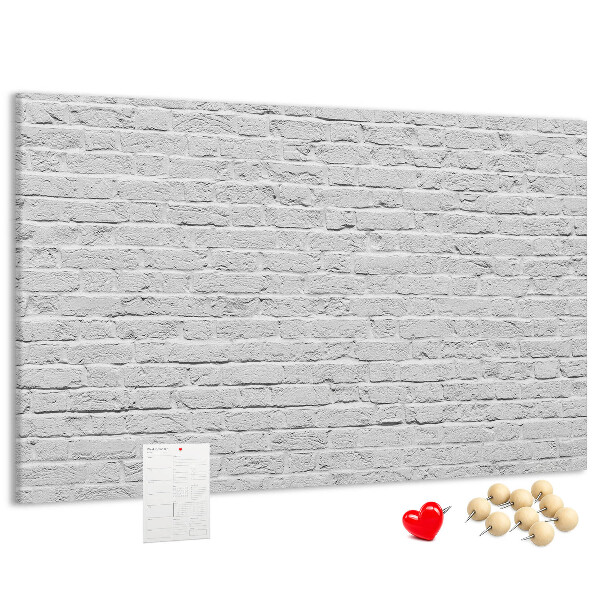 Tablero de anuncios con diseño de pared de ladrillo blanco y chinchetas de colores