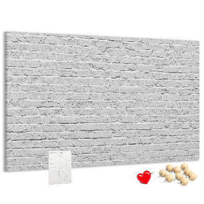 Tablero de anuncios con diseño de pared de ladrillo blanco y chinchetas de colores