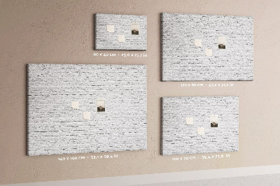 Tablero de anuncios con diseño de pared de ladrillo blanco y chinchetas de colores