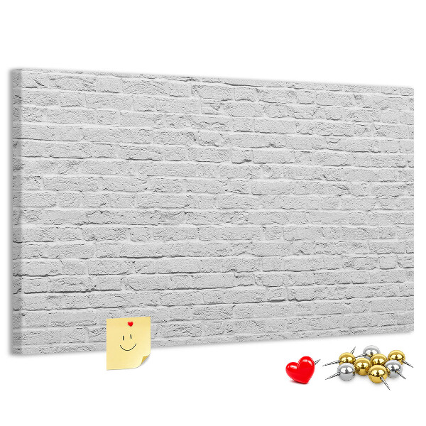 Tablero de anuncios con diseño de pared de ladrillo blanco y chinchetas de colores