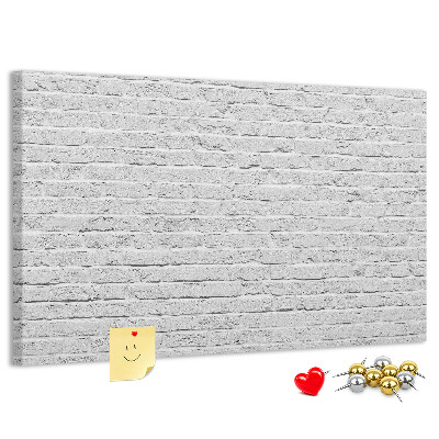 Tablero de anuncios con diseño de pared de ladrillo blanco y chinchetas de colores