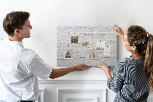 Tablero de anuncios con diseño de pared de ladrillo blanco y chinchetas de colores