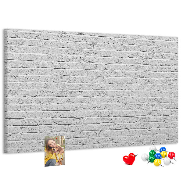 Tablero de anuncios con diseño de pared de ladrillo blanco y chinchetas de colores