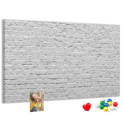 Tablero de anuncios con diseño de pared de ladrillo blanco y chinchetas de colores