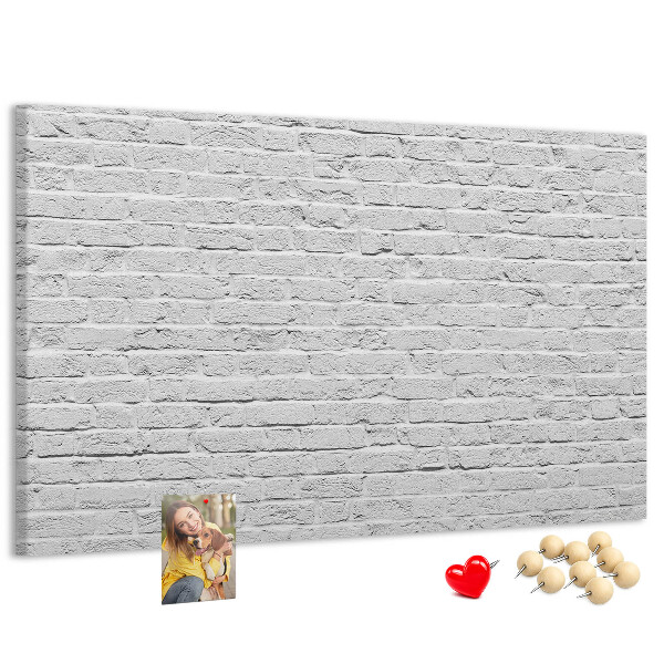 Tablero de anuncios con diseño de pared de ladrillo blanco y chinchetas de colores