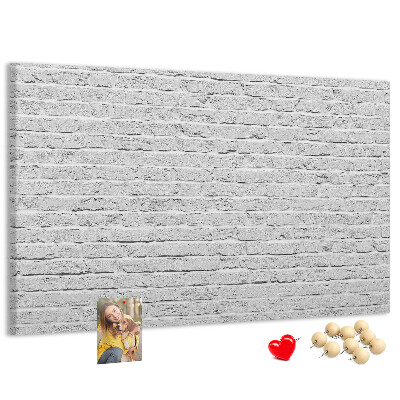 Tablero de anuncios con diseño de pared de ladrillo blanco y chinchetas de colores