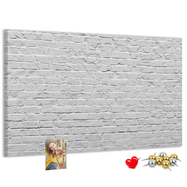 Tablero de anuncios con diseño de pared de ladrillo blanco y chinchetas de colores