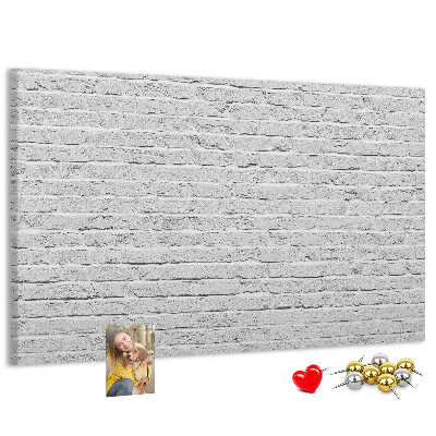 Tablero de anuncios con diseño de pared de ladrillo blanco y chinchetas de colores