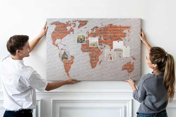 Tablero de corcho decorado Un mapamundi contra una pared de ladrillos
