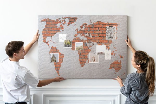 Tablero de corcho decorado Un mapamundi contra una pared de ladrillos