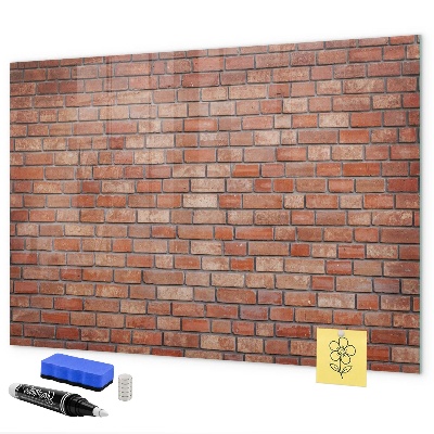 Pizarra borrable de cristal con imanes Un tablero de notas en una pared de ladrillos.