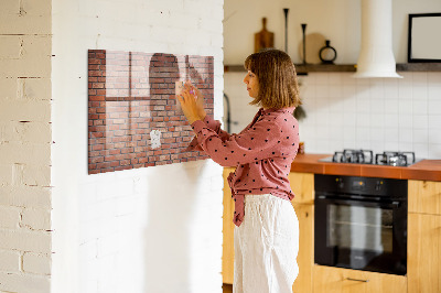Pizarra borrable de cristal con imanes Un tablero de notas en una pared de ladrillos.