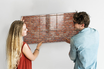 Pizarra borrable de cristal con imanes Un tablero de notas en una pared de ladrillos.