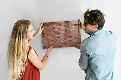 Pizarra borrable de cristal con imanes Un tablero de notas en una pared de ladrillos.