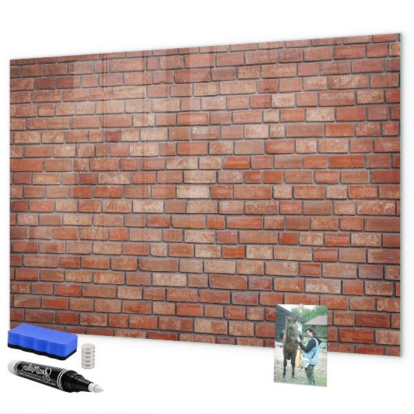 Pizarra borrable de cristal con imanes Un tablero de notas en una pared de ladrillos.