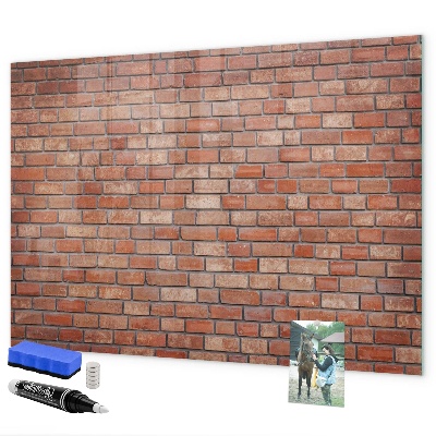 Pizarra borrable de cristal con imanes Un tablero de notas en una pared de ladrillos.
