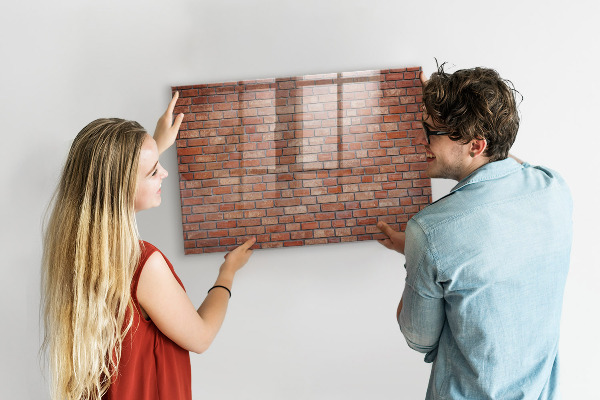 Pizarra borrable de cristal con imanes Un tablero de notas en una pared de ladrillos.