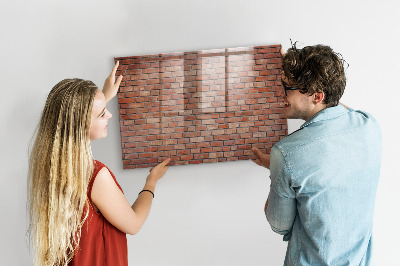 Pizarra borrable de cristal con imanes Un tablero de notas en una pared de ladrillos.